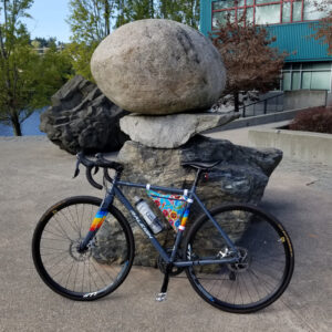 A Raleigh RXM cyclocross bike featuring a blue floral oilcloth frame bag rests against a stone sculpture